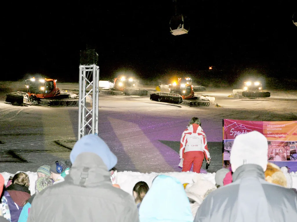 Pistenraupen im Scheinwerferlicht bei der Abendveranstaltung.